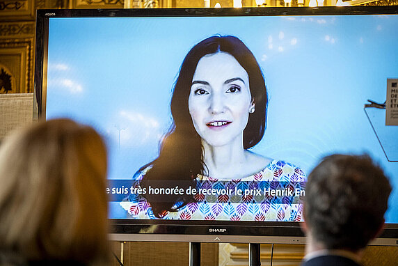 Stefanie Stantcheva accepts the Henrik Enderlein Prize remotely via video call. She is pictured on a large screen, her words subtitled in French.